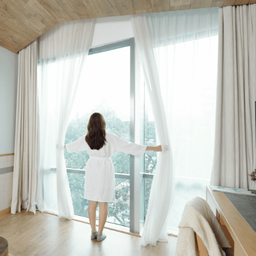 Mevrouw opent een inbetween gordijn nadat ze haar gordijnen heeft geopend.