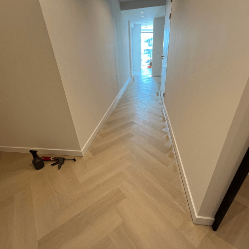 sfeervolle lange gang met pvc visgraatvloer en strakke witte randafwerking